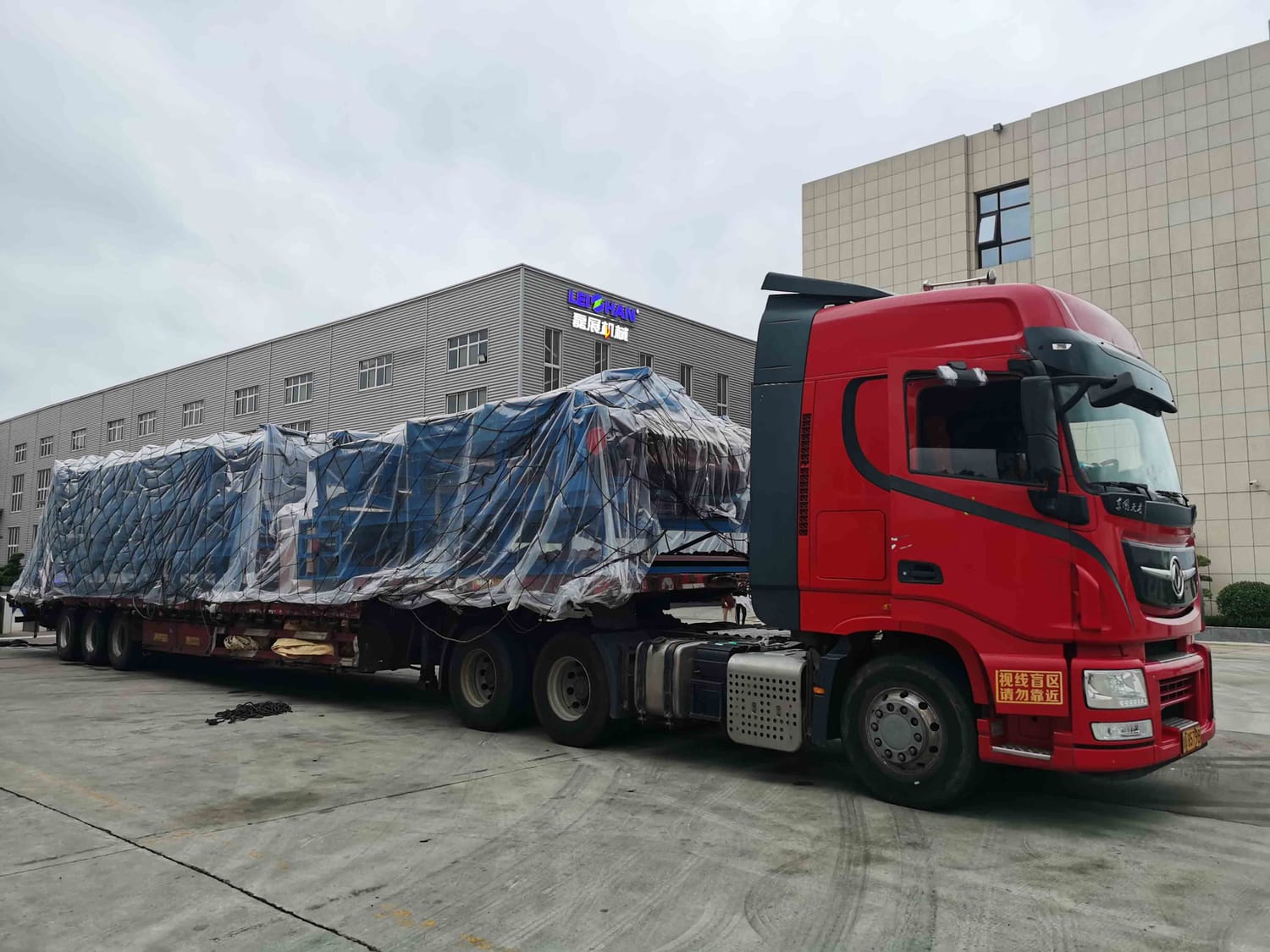 Camion cu semiremorcă platformă transportând un utilaj ambalat